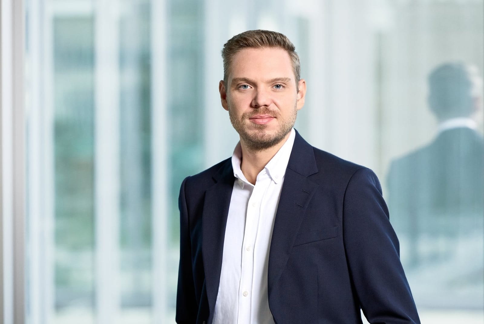 Person in a suit standing in front of a window.